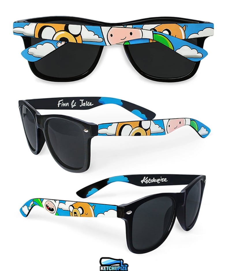 Picture of black sunglasses, hand-painted with an Adventure Time inspired design, including Finn the human and Jake the dog on a blue background with white clouds, in white, blue and yellow colors.