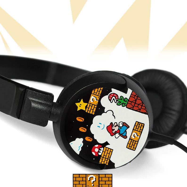 Picture of black headphones, hand-painted with a Super Mario 8 bit video game inspired design. Including the Mario brothers, Mario and Luigi, 1up mushrooms, Piranha plant, Question blocks, Starman and Brick Blocks on a black background.