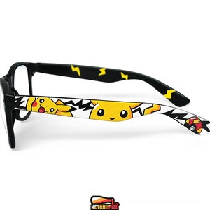 Picture of black clear lens glasses, hand-painted with a Pokemon design, including yellow Pikachu, black bolts and red and white Pokeballs on a white background, in white, black, yellow and red colors.