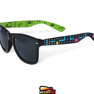 Picture of black sunglasses, hand-painted with an Arcade video game inspired design, including yellow, red, pink, orange and blue monsters and ghosts, white dots and blue lines.