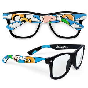 Picture of black clear lens glasses, hand-painted with an Adventure Time inspired design, including Finn the human and Jake the dog on a blue background with white clouds, in white, blue and yellow colors.