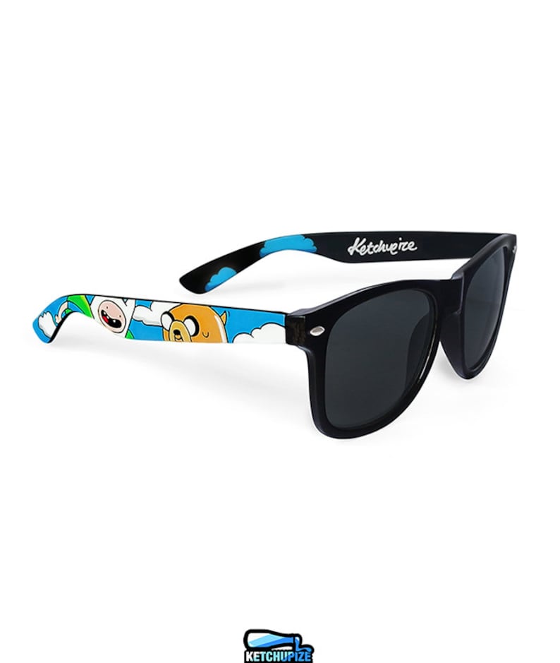 Picture of black sunglasses, hand-painted with an Adventure Time inspired design, including Finn the human and Jake the dog on a blue background with white clouds, in white, blue and yellow colors.