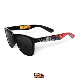 Picture of black sunglasses, hand-painted with a Spiderman comic theme design, showing Spiderman against spider web and the city skyline, in red, blue and black colors.