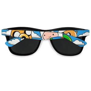 Picture of black sunglasses, hand-painted with an Adventure Time inspired design, including Finn the human and Jake the dog on a blue background with white clouds, in white, blue and yellow colors.