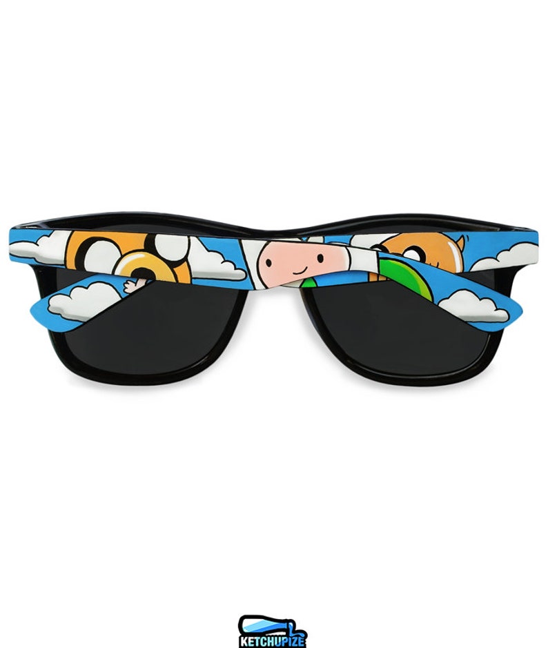Picture of black sunglasses, hand-painted with an Adventure Time inspired design, including Finn the human and Jake the dog on a blue background with white clouds, in white, blue and yellow colors.