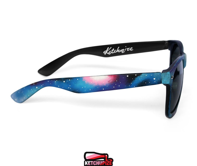 Picture of black sunglasses, hand-painted with a galaxy design in blue, purple and pink colors.