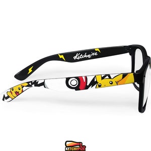 Picture of black clear lens glasses, hand-painted with a Pokemon design, including yellow Pikachu, black bolts and red and white Pokeballs on a white background, in white, black, yellow and red colors.