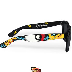 Picture of black sunglasses, hand-painted with a Pokemon design, including yellow Pikachu, blue and white bolts and red and white Pokeballs on a black background, in white, black, yellow, red and blue colors.