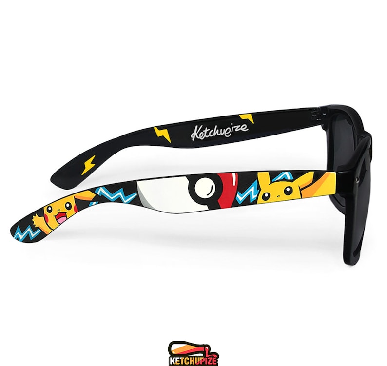 Picture of black sunglasses, hand-painted with a Pokemon design, including yellow Pikachu, blue and white bolts and red and white Pokeballs on a black background, in white, black, yellow, red and blue colors.