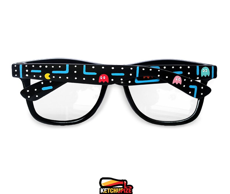 Picture of black prescription glasses, hand-painted with an Arcade video game inspired design, including yellow, red, pink, orange and blue monsters and ghosts, white dots and blue lines.