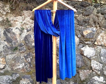 May include: Two blue velvet scarves hanging on a wooden rack. The scarf on the left is a deep blue, while the scarf on the right is a lighter blue with a gradient effect.