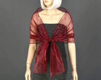 May include: A burgundy sheer shawl with a satin-like finish. The shawl is tied in a knot at the front and drapes over the shoulders.