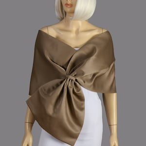 May include: A brown satin shawl with a large bow at the front. The shawl is draped over a mannequin's shoulders.