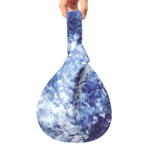 May include: A blue and white tie-dye fabric tote bag with a knotted handle.
