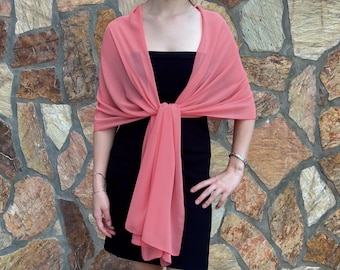 May include: A coral pink chiffon shawl draped over a black dress. The shawl is tied at the neck and hangs down to the waist.