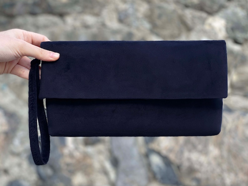 Op de afbeelding: Een zwarte clutch van fluweel met een enkele band.
