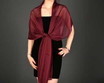 May include: A burgundy sheer shawl with a long, flowing end. The shawl is tied around the neck and drapes down the front of the body.