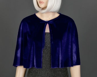 May include: A royal blue velvet cape with a tie closure. The cape is short and has a rounded hem.