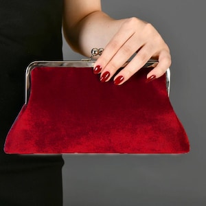 May include: A red velvet clutch bag with a silver clasp.