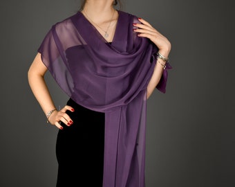 Pode incluir: Um xale de seda roxo drapeado sobre um vestido preto. O xale é feito de um tecido leve e tem um visual fluido e elegante.