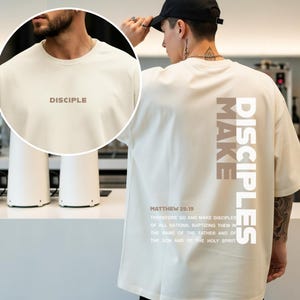 Peut inclure: T-shirt crème avec le mot "DISCIPLE" imprimé sur le devant. Le dos du t-shirt présente les mots "MAKE DISCIPLES" verticalement, ainsi qu'un verset biblique de Matthieu 28:19.