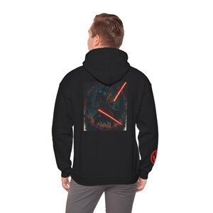 May include: Black hooded sweatshirt featuring a graphic of a figure with red lightsabers and text. The design is on the back of the sweatshirt. A red logo is on the right sleeve. The sweatshirt is made of a soft, comfortable material.