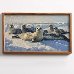 May include: A framed print of seals resting on an icy surface. The seals are various sizes and colors, with gray and white fur. The background shows a blue ocean and a cloudy sky. The frame is made of wood.