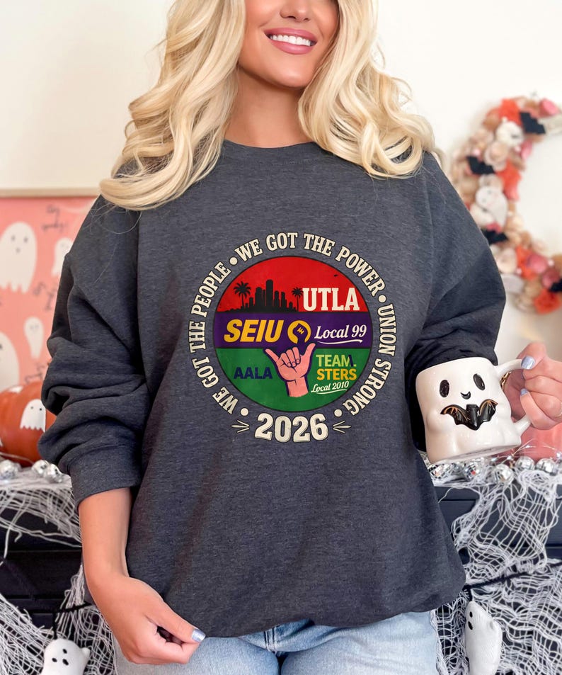 May include: Dark gray sweatshirt with a circular graphic. The graphic includes the text "WE GOT THE POWER" and "UTLA SEIU Local 99 UNION STRONG" with a hand symbol and the year "2026". The sweatshirt is a crew neck style.