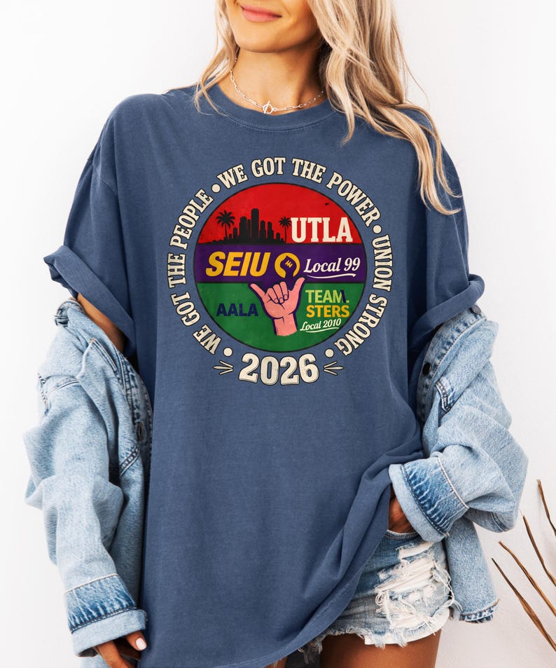 May include: A navy blue t-shirt with a circular graphic featuring the text "WE GOT THE POWER" and union logos. The graphic includes the text "UTLA", "SEIU Local 99", "TEAMSTERS Local 2010", and "2026". The shirt has rolled-up sleeves.