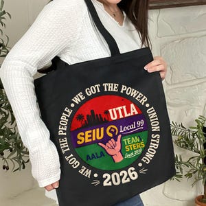 May include: Black tote bag with a circular graphic featuring the text "WE GOT THE POWER" and "UNION STRONG." The graphic includes the text "UTLA," "SEIU Local 99," "TEAMSTERS Local 2010," and "2026." A hand gesture is also visible.