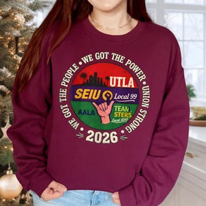 May include: Burgundy sweatshirt with a circular graphic. The graphic includes text that reads "WE GOT THE POWER" and "UNION STRONG". It also features the text "UTLA", "SEIU Local 99", "AALA", "TEAM STERS Local 2010", and "2026".