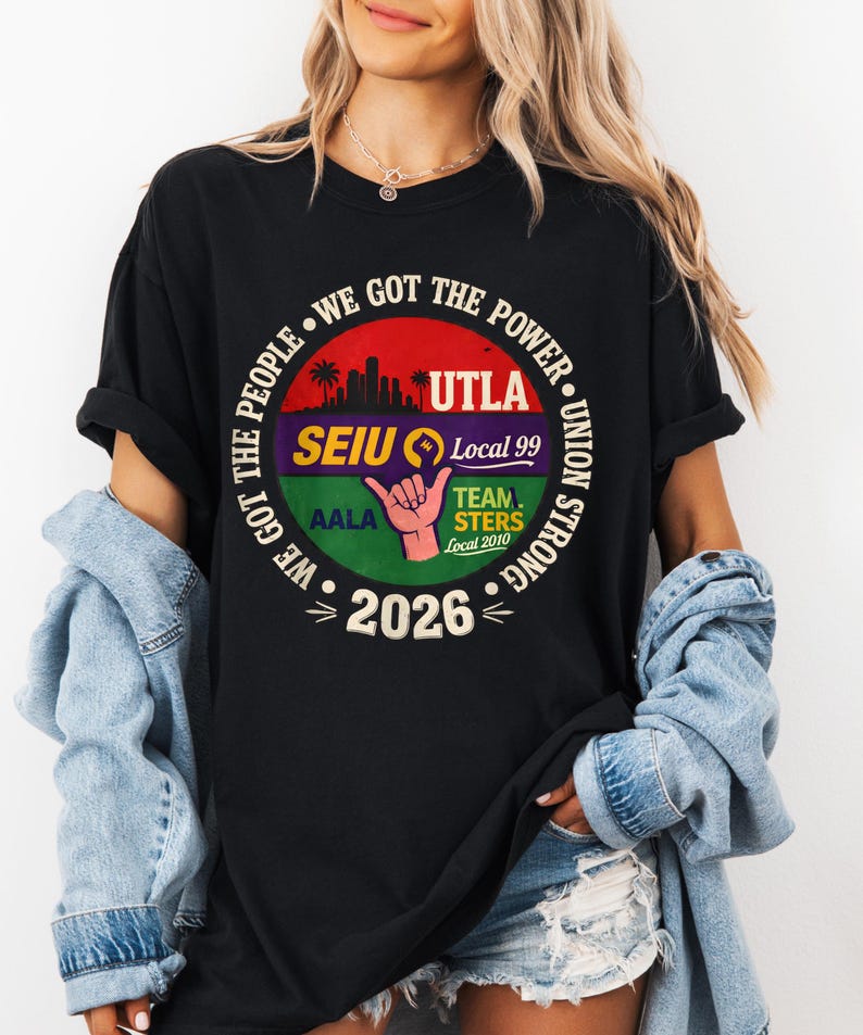 May include: Black t-shirt with a circular graphic featuring the text "WE GOT THE POWER" and "UNION STRONG." The graphic includes the text "UTLA," "SEIU Local 99," "TEAMSTERS Local 2010," and "2026." A hand gesture is also visible.