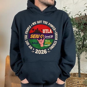 May include: Navy blue hooded sweatshirt with a circular graphic. The graphic includes the text "WE GOT THE PEOPLE" and "WE GOT THE POWER" around a central design with the text "UTLA", "SEIU Local 99", "TEAMSTERS Local 2010", and "2026".