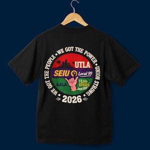 May include: Black t-shirt with a circular graphic on the back. The graphic features text that reads "WE GOT THE POWER" and "UNION STRONG" around a central design. The design includes a cityscape, a hand gesture, and the text "UTLA", "SEIU Local 99", "AALA", "TEAMSTERS Local 2010", and "2026".