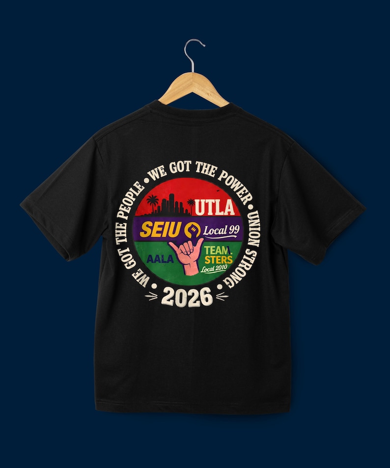 May include: Black t-shirt with a circular graphic on the back. The graphic features text that reads "WE GOT THE POWER" and "UNION STRONG" around a central design. The design includes a cityscape, a hand gesture, and the text "UTLA", "SEIU Local 99", "AALA", "TEAMSTERS Local 2010", and "2026".