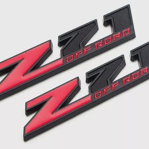 May include: Two black and red "Z71 OFF ROAD" emblem badges. The "Z71" is red with a black outline, and the "OFF ROAD" text is red. The badges have a textured surface.