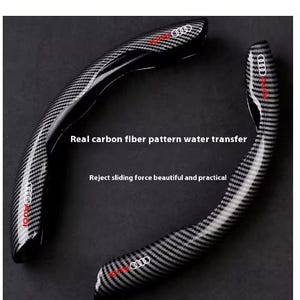 Könnte beinhalten: Zwei schwarze und graue Lenkradbezüge für Autos mit Carbonfasermuster. Die Bezüge haben das Audi-Logo in Rot und Weiß. Auf den Bezügen steht "Real carbon fiber pattern water transfer" und "Reject sliding force beautiful and practical."