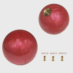 Peut inclure: Deux boutons sphériques rouges avec un éclat métallique. L'un des boutons a un insert en laiton fileté. Trois inserts en laiton avec le texte "M 8*1.25 M 10*1.5 M 10*1.25" sont en dessous. Ce sont probablement des pièces de rechange.
