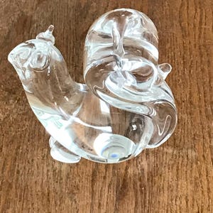 May include: A white ceramic mug with a black handle and the text "But First, Coffee" in a black, bold font. The mug is on a white surface.