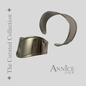 May include: Two silver-toned metal cuff bracelets. One is a curved open design, and the other is a wider band with a curved edge. The text "The Curated Collection" and "Annice .co.uk" are visible.