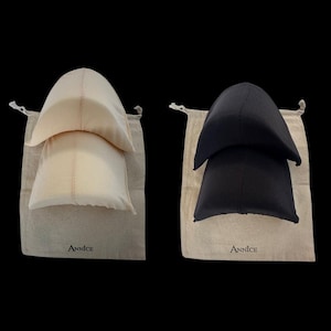 May include: Two sets of head coverings, one in cream and the other in black, each nestled in a drawstring bag. The bags are beige and bear the brand name "Annice" in a simple font. The head coverings have a rounded, layered design.