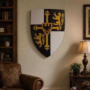 May include: A decorative shield with a black, white, and gold design, mounted on a wall. The shield features a cross design with heraldic symbols, including a golden lion and eagle. The shield is a decorative item for home decor.