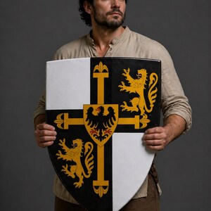 May include: A medieval shield with a black, white, and gold design. The shield features a cross design with a central eagle emblem and two golden lions. The shield is held in front of a person.