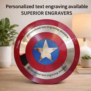 Puede incluir: Un escudo redondo rojo, blanco y azul con un borde plateado y una estrella central. El escudo tiene el texto "Personalized text engraving available" y "SUPERIOR ENGRAVERS".