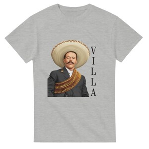 May include: Gray t-shirt featuring a portrait of a man in a sombrero and military attire. The word "VILLA" is printed vertically on the right side of the shirt. The man has a large mustache.