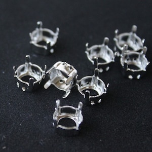 Puede incluir: Ajustes de metal plateados para diamantes de imitación u otros adornos. Los ajustes son redondos con seis garras y una base plana.