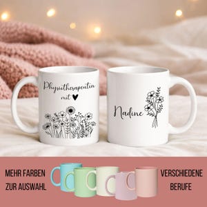 Könnte beinhalten: Zwei weiße Keramikbecher mit schwarzem Text und Blumendesigns. Auf einem Becher steht "Physiotherapeutin mit" mit einem Herz, auf dem anderen "Nadine". Darunter eine Reihe farbiger Becher in Blau, Grün, Creme, Rosa und Pfirsich.