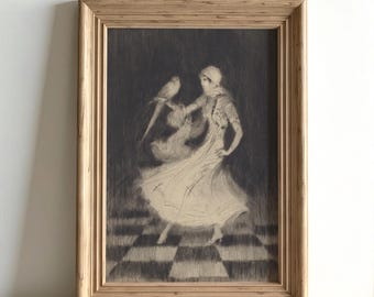 Könnte beinhalten: Ein gerahmter Schwarz-Weiß-Druck einer Frau, die mit einem Vogel tanzt. Die Frau trägt ein langes Kleid und eine Kopfbedeckung. Der Hintergrund ist dunkel, und der Boden hat ein Schachbrettmuster. Der Rahmen ist aus hellem Holz.