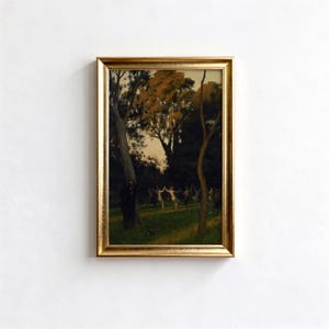 May include: A framed landscape painting with a gold-colored frame. The artwork depicts a forest scene with trees, a grassy area, and figures in the distance. The color palette includes greens, browns, and hints of gold.
