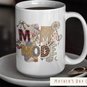 May include: A white ceramic mug with a black handle and the text "But First, Coffee" in a bold, black font. The mug is set against a blurred background, suggesting a cozy setting.